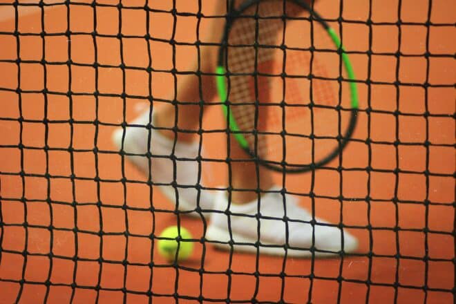 Tennisspieler vorm Netz mit Schläger und Ball
